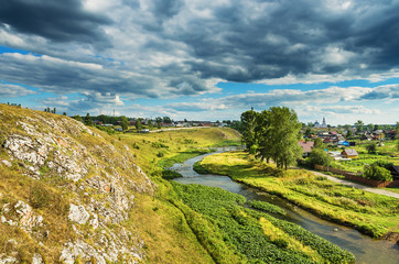 Summer rural landscape with river, rocks and clouds