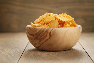rippled potato chips with paprika in wooden bowl, with copy space