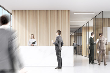 Two men in suits are discussing work in a corner of an office hall. There is a white reception desk and a corridor in the background. 3d rendering. Mock up.