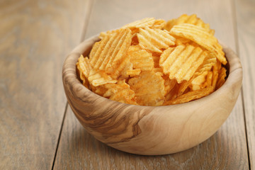 rippled potato chips with paprika in wooden bowl, with copy space