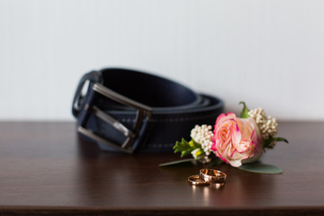 Groom's morning. Wedding accessories on wooden background. A belt, rings, watch, boutonniere. Preparing to wedding day