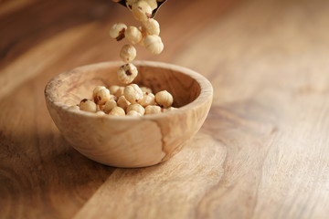 roasted hazelnuts falling in wood bowl on wooden table, copy space on the right side
