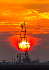 Obsolete oil and gas rig profiled on dramatic evening sky