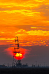 Obsolete oil and gas rig profiled on dramatic evening sky