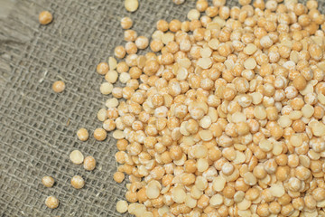 Top view of Dry yellow split peas chickpeas on burlap texture ba