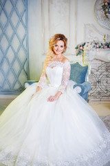 Fototapeta premium Portrait of charming woman in wedding dress. The girl bride sits in a chair