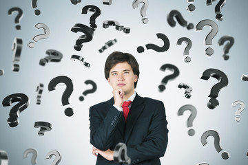 Pensive businessman and falling question marks