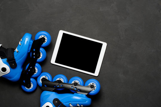 Sport, healthy lifestyle, roller skates and tablet on dark chalk board background