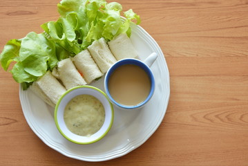 roll bread filled bologna and green oak with coffee on plate