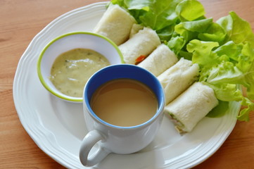 roll bread filled bologna and green oak with coffee on dish