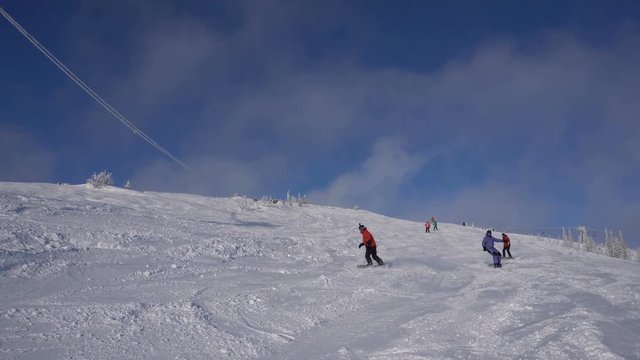 Snowboarders are going down from top of the mountain