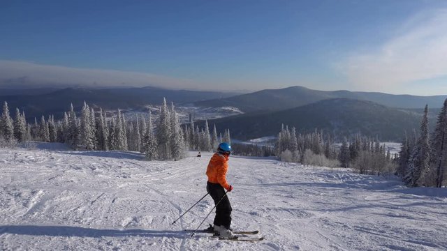 Woman skier goes down from mountain's top at sunny day