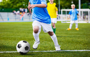 Running Soccer Player. Children Football Soccer Match. Kids Playing Soccer Game Tournament. Boys Running and Kicking Football. Youth Soccer Stadium in the Background