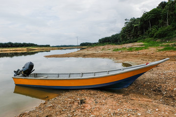 Fototapeta premium fiber boat anchored near the lake shore. reflection and cloudy sky background