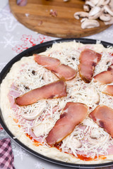 Raw prepared pizza with domestic sirloin and sausages