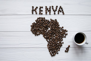 Map of the Kenya made of roasted coffee beans laying on white wooden textured background with  cup of coffee and space for text