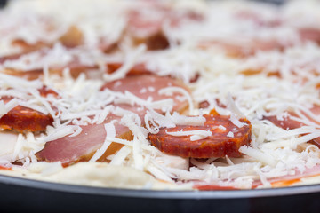 Raw prepared pizza with domestic sirloin and sausages