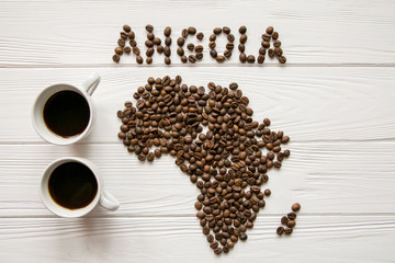 Map of the Africa made of roasted coffee beans and two cups of coffee on white wooden textured background with space for text