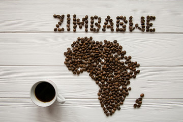 Map of the Africa made of roasted coffee beans and cup of coffee on white wooden textured background with space for text