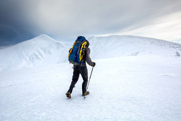 Man hiking in winter mountains before thunderstorm