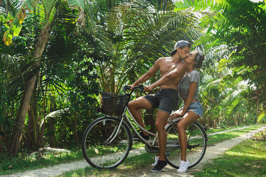 Young couple ride a bicycle by country road  in warm country
