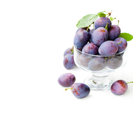 Fresh  ripe plums in a glass bowl on white background