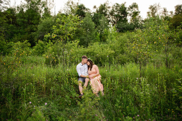 Fototapeta na wymiar Couple in love sitting on green grass in spring or summer garden. Love and relationship of young couple