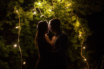 Couple in love, mysterious silhouette of woman and man near lights at night. Secret of love concept