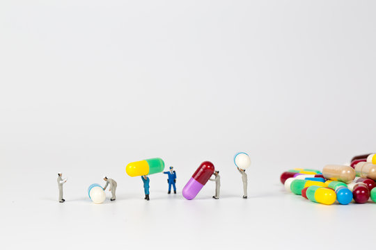 Drug Capsule With Miniature People On White Background