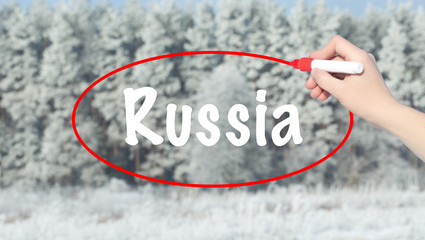 Woman Hand Writing Russia with a marker over winter forest.