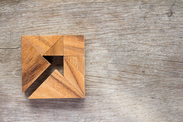 Naklejka na ściany i meble Tangram puzzle as arrow in square shape on wooden background