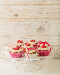 Cupcakes with white icing decorated with pink candy and ribbons.