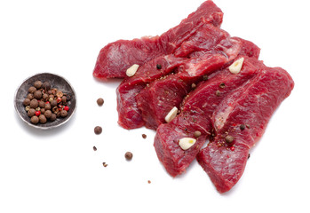 Pieces of meat with garlic isolated on white background. Raw beef. Top view.