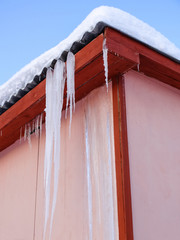 Icicles on the roof of the buildings covered with snow