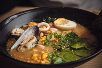 Bowls of Asian soup with seafood, eggs, onion