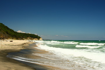 Beautiful sunny beach with blue sky, white waves and dark-golden sand on the Black sea