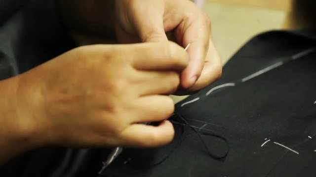 Sewing a button onto a bespoke tailored suit