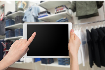 human hand hold and touch smartphone, tablet, cell phone with blurry clothing store.