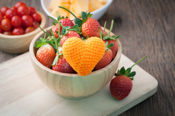 fresh ripe strawberry on wood plate with orange heart shape , red tasty fruit on kitchen table. healthy eating and dieting food, concept of health care, Image focus top view.