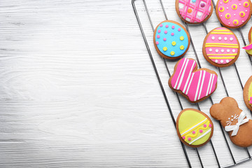 Decorative gingerbread Easter cookies on baking wire rack and white wooden background