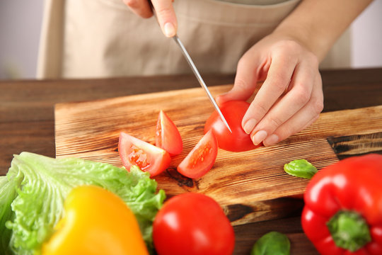 Woman chopping fresh vegetables on cutting board