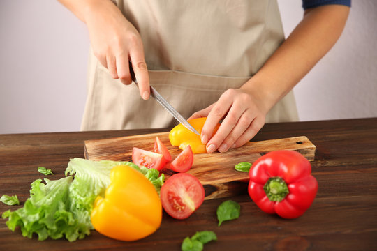 Woman chopping fresh vegetables on cutting board