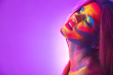 Portrait of attractive young woman with bright facial body-art on purple background