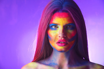 Obraz premium Portrait of attractive young woman with bright facial body-art on purple background