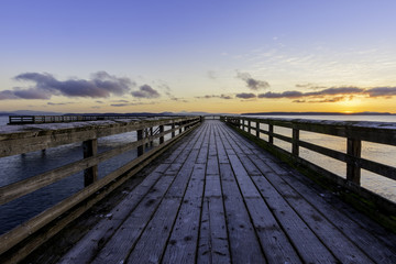 Fototapeta na wymiar Early morning on frosty ocean pier with orange sky.Vancouver Island Canada