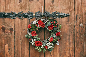 Floral wreath with beautiful flowers hanging on wooden background