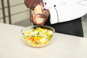 African American chef cooking tasty salad in kitchen, closeup
