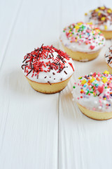 Cupcakes with white cream  and sprinkles on white background