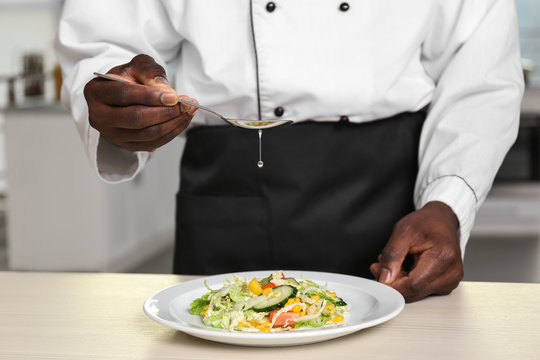 African American chef cooking tasty salad in kitchen, closeup