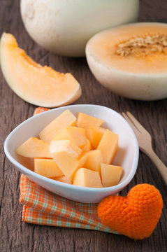 kitchen table with  slice fresh cantaloupe melon on white plate.